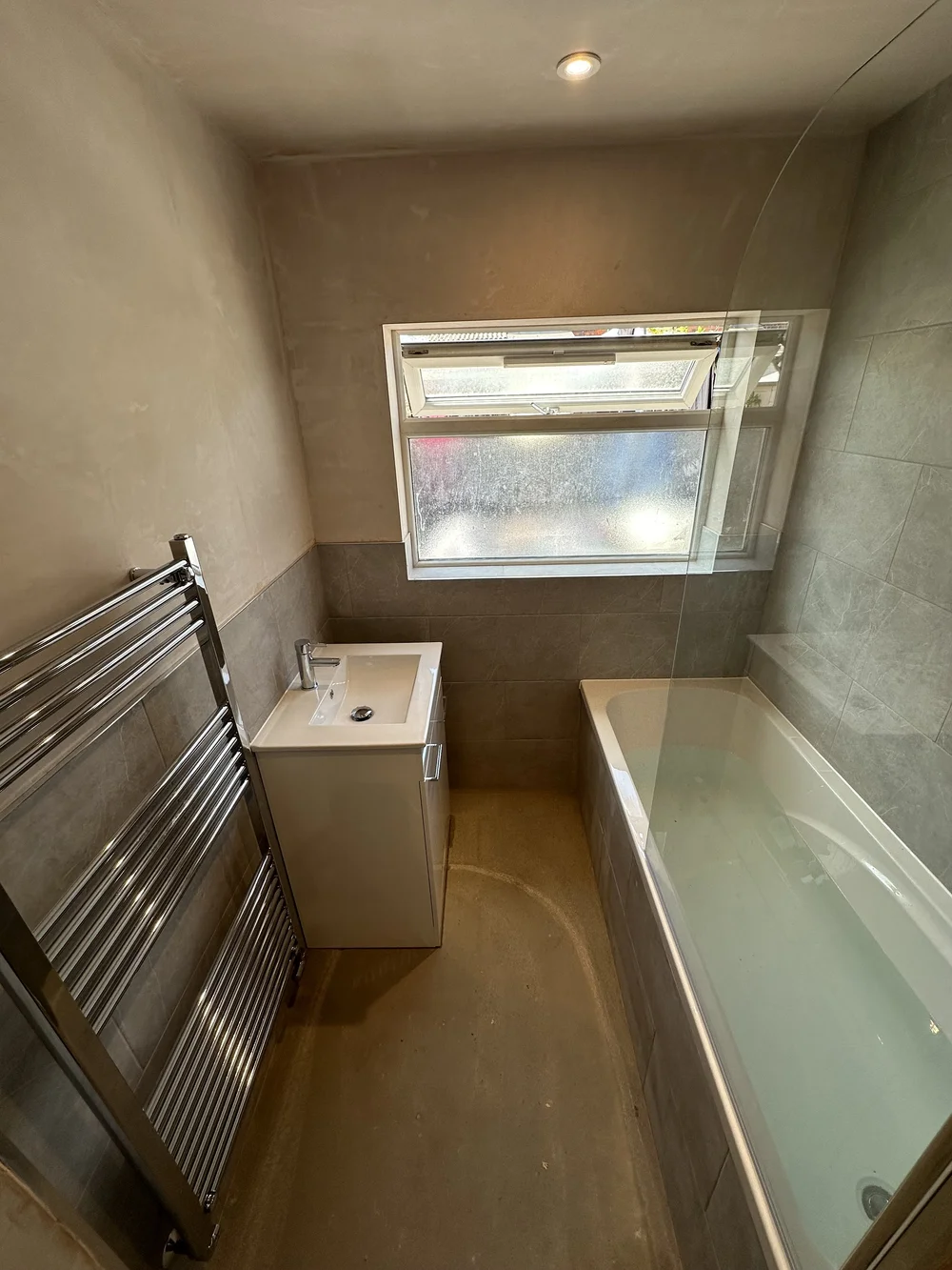 Bathroom mid-renovation with new bath, vanity and chrome towel radiator