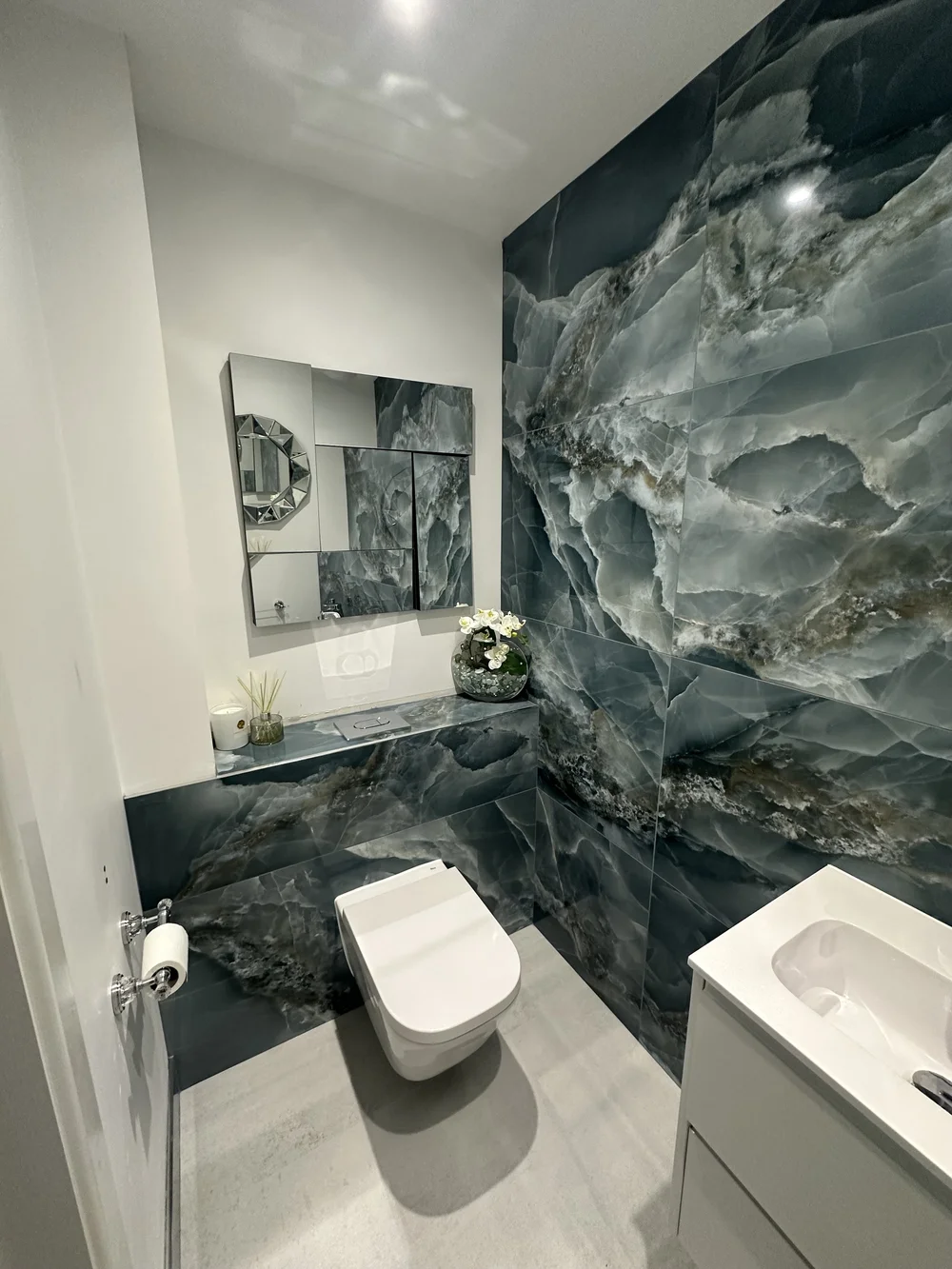 Cloakroom with full blue onyx feature wall and wall-hung WC