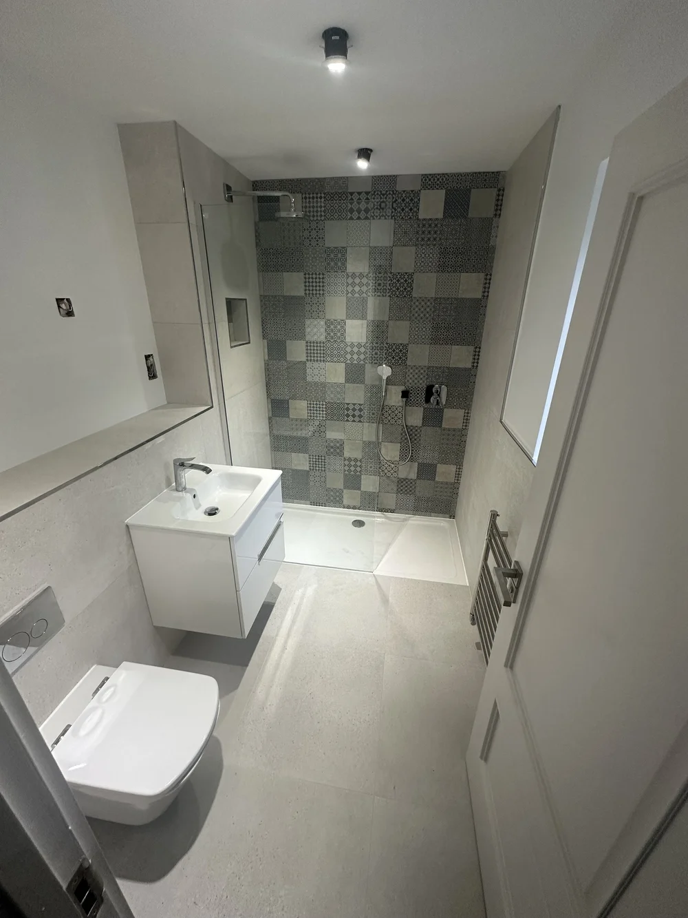 Shower room with patchwork encaustic feature wall and floating vanity