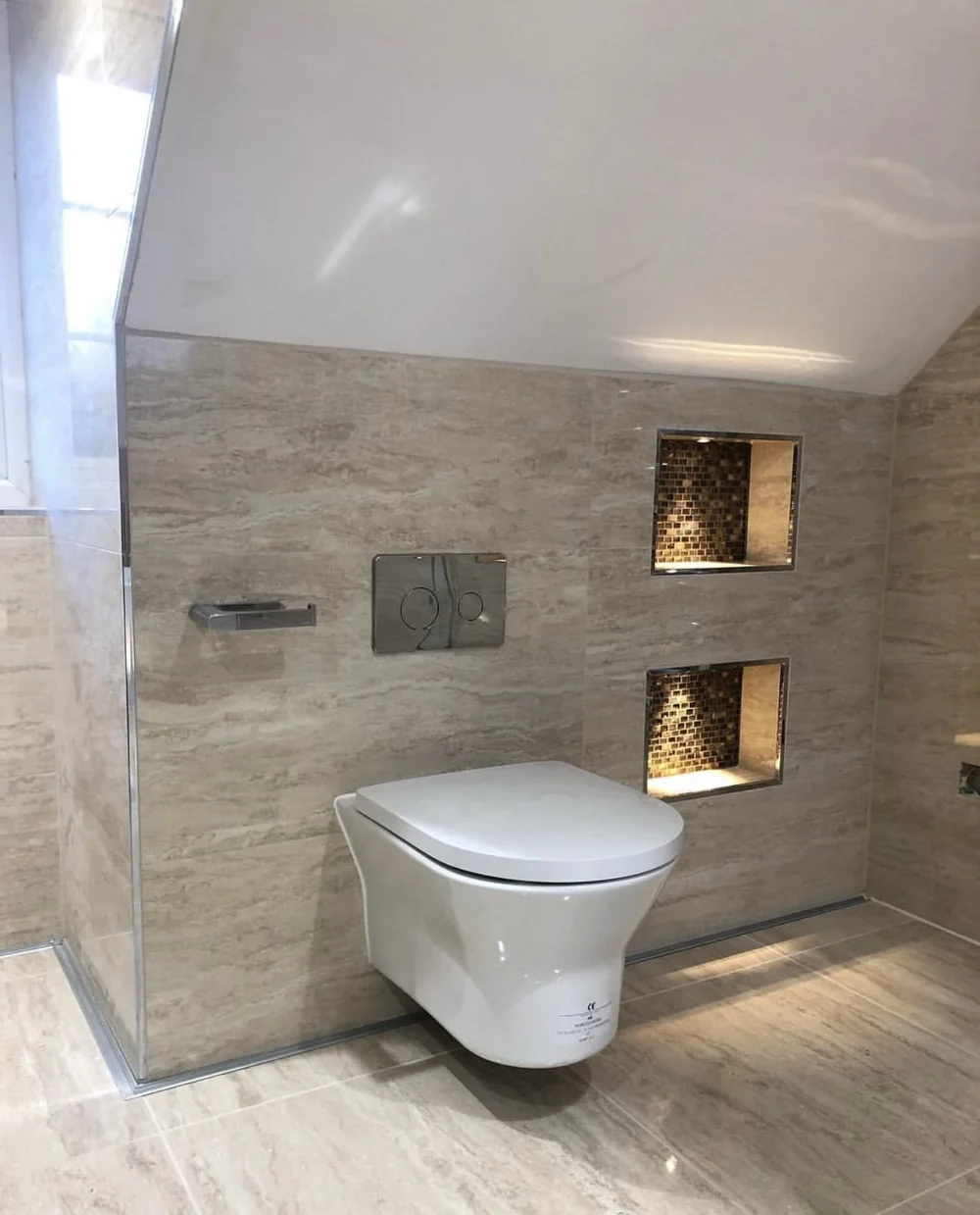 Travertine-tiled loft bathroom with wall-hung WC and mosaic niches