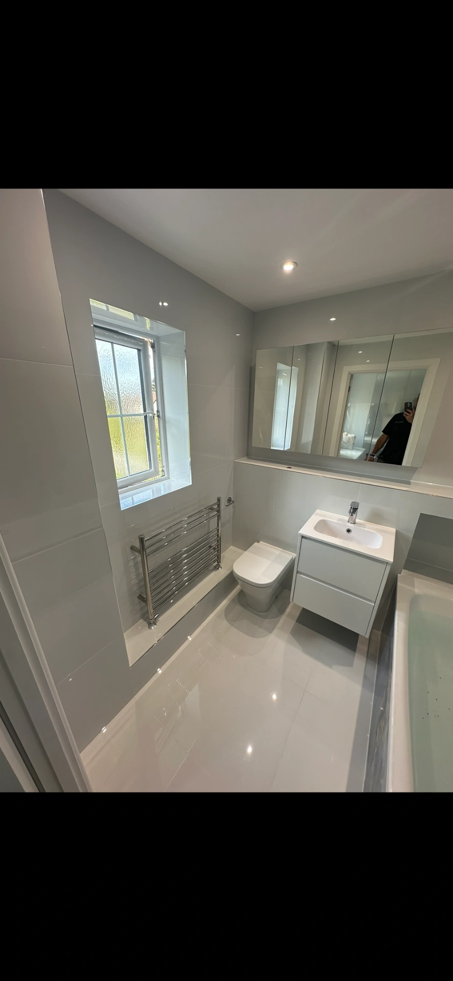 Bright white family bathroom with chrome towel radiator and vanity unit