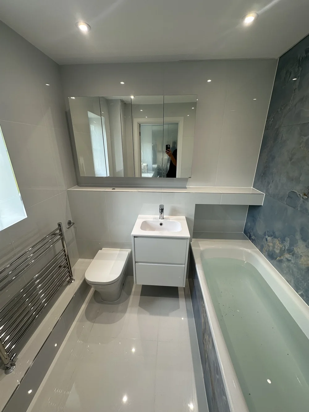 Modern family bathroom with blue marble feature wall and mirrored cabinet