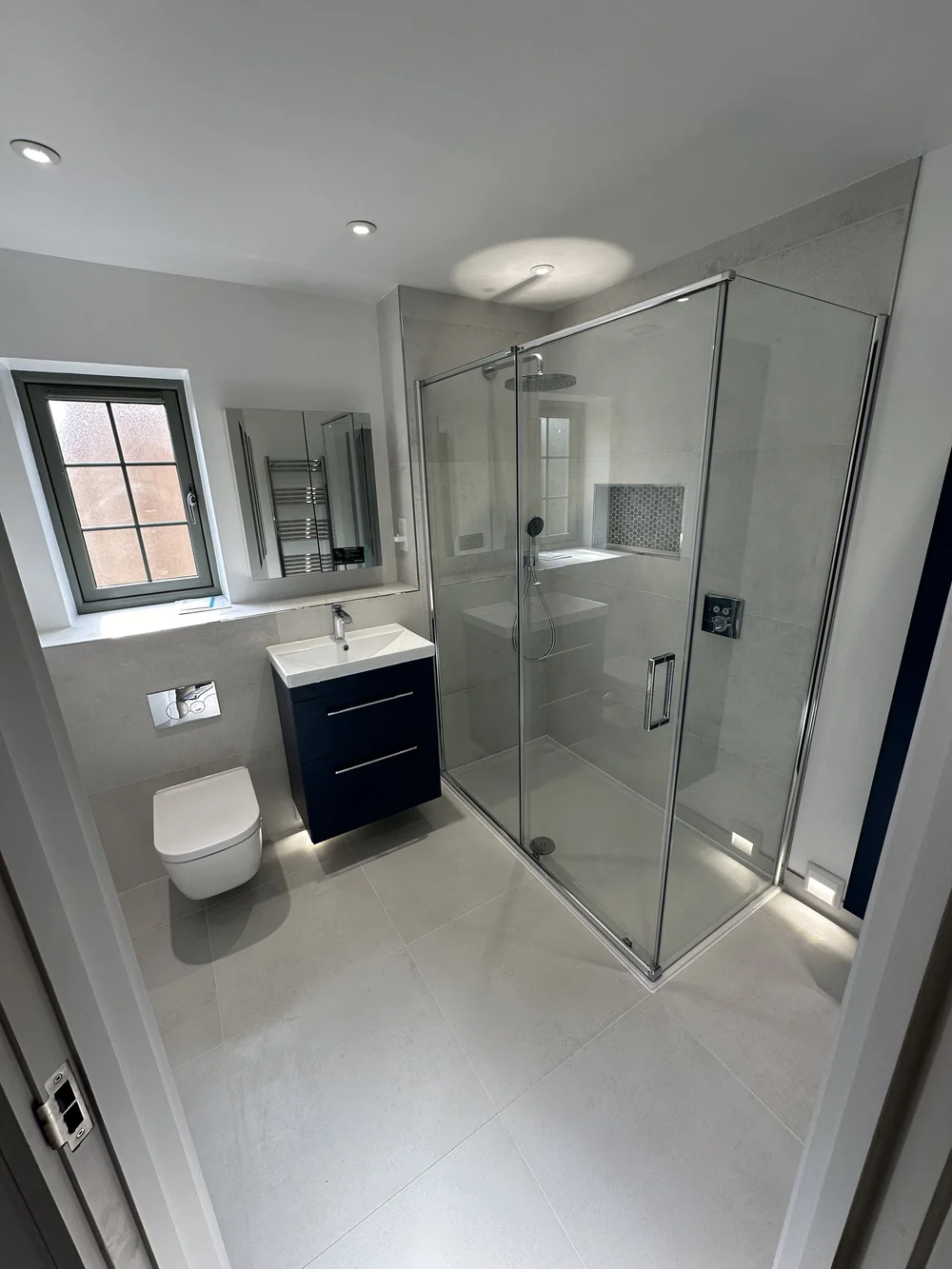 Modern ensuite with large sliding-door shower enclosure and navy vanity