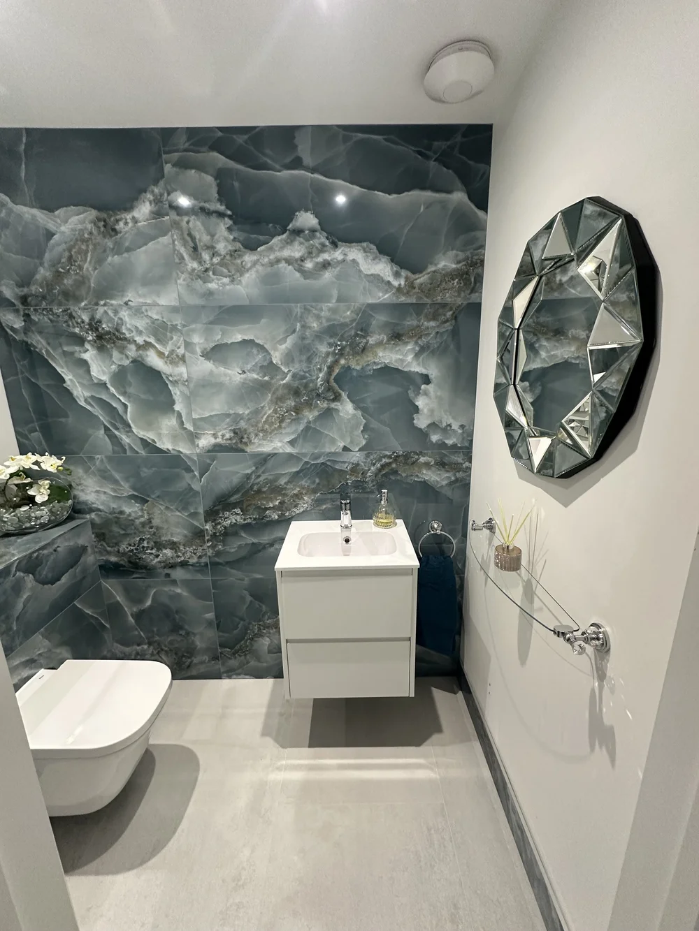 Cloakroom with dramatic blue onyx feature wall and geometric mirror