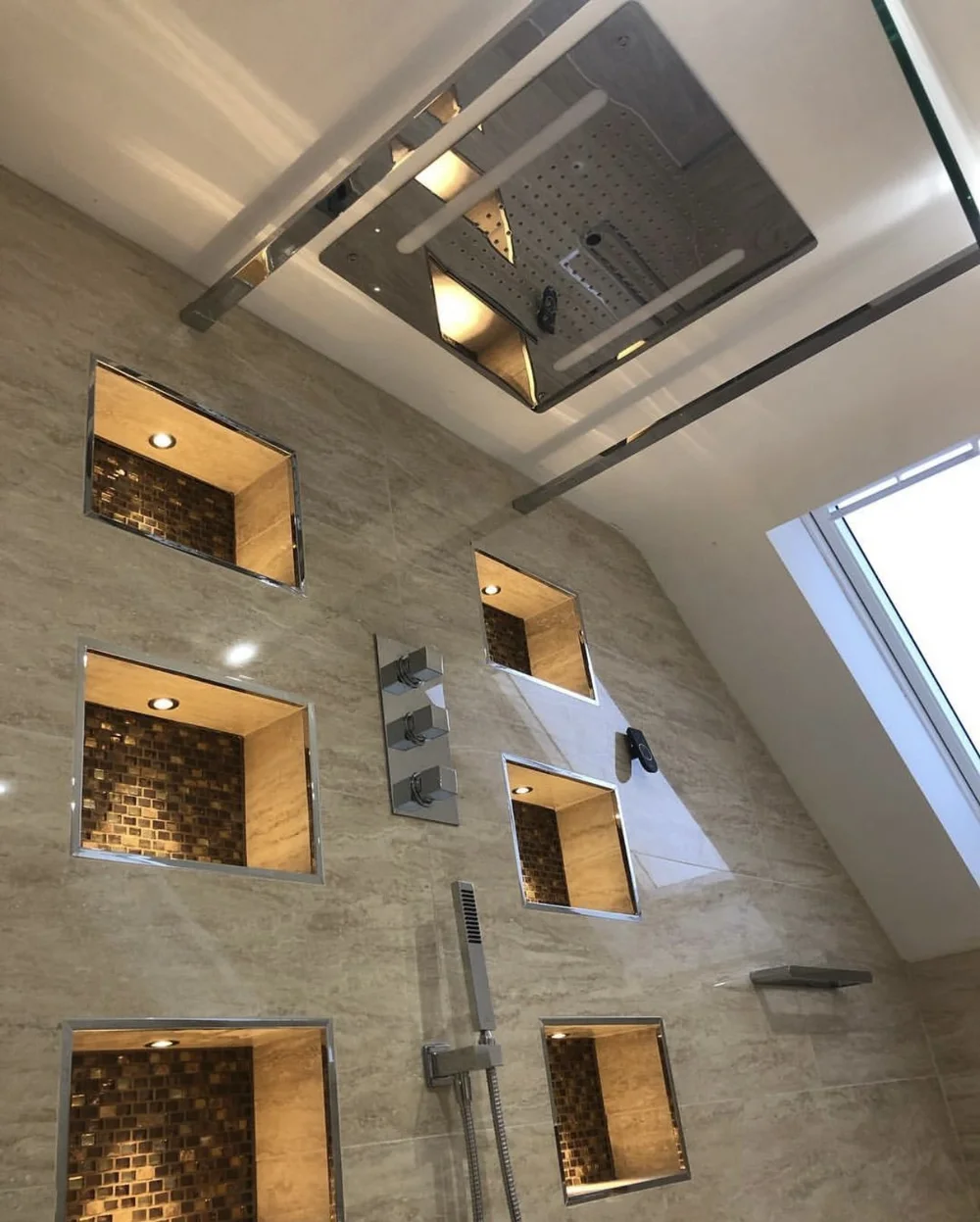 Luxury shower with ceiling rainfall panel and lit mosaic display niches
