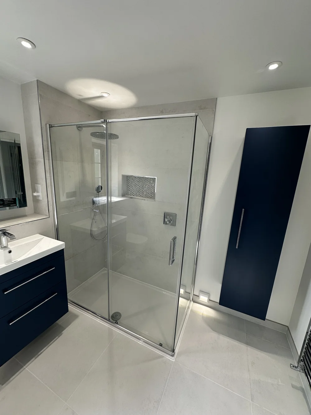 Bathroom with large shower enclosure and tall navy storage cabinet