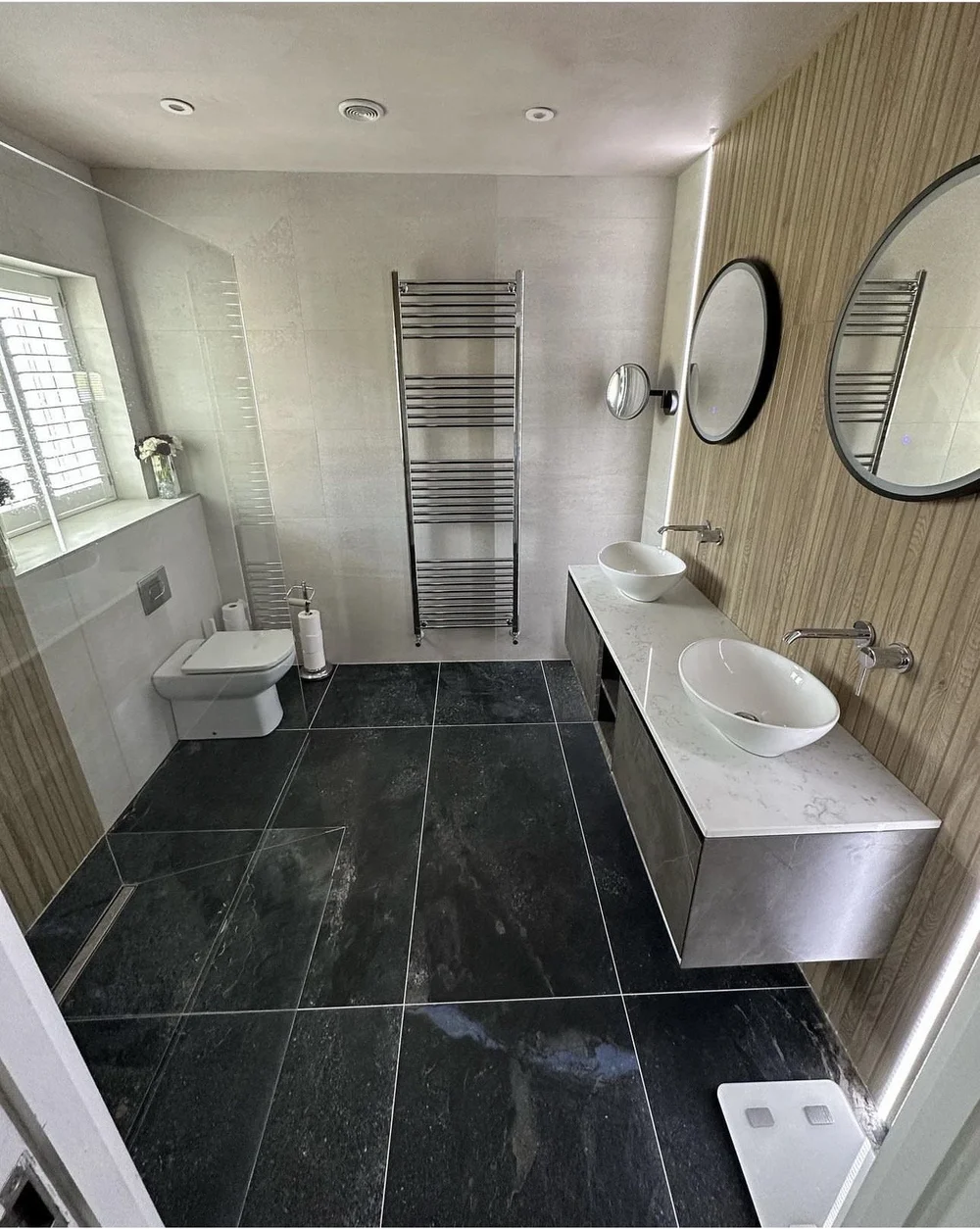 Luxury bathroom with slate floor, twin vessel basins and wood panelling