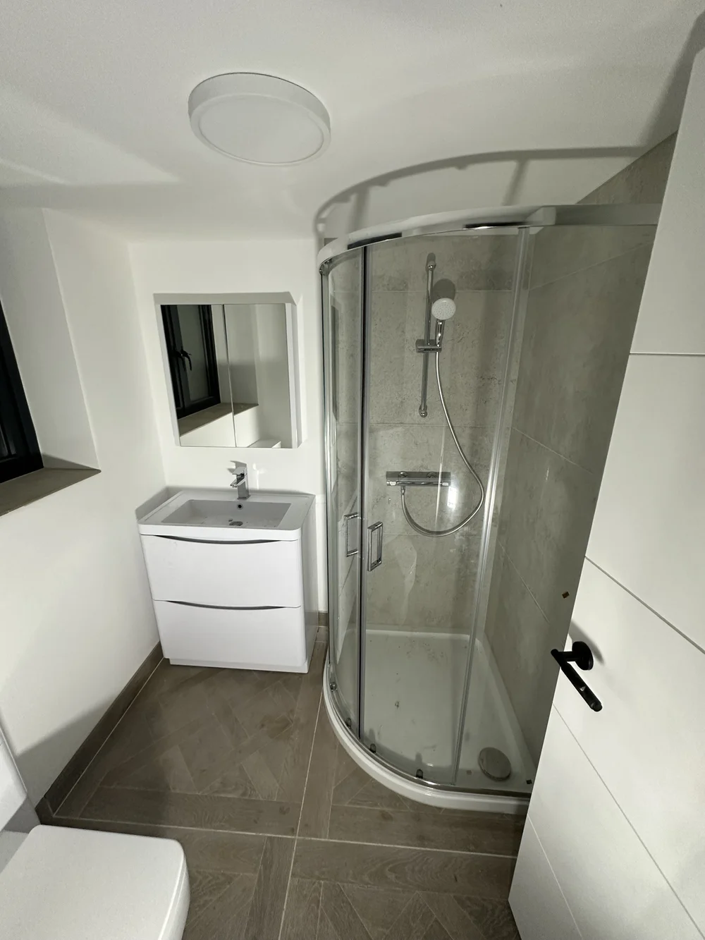 White ensuite with quadrant shower enclosure and wood-effect tiled floor
